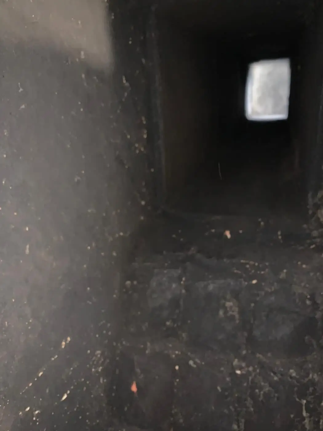 Vista hacia arriba de un conducto oscuro con residuo en las paredes, hacia la abertura de arriba.